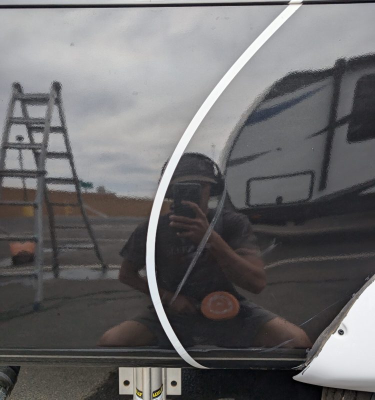 a professional detailer taking a picture of himself in the reflective paint to show the before results