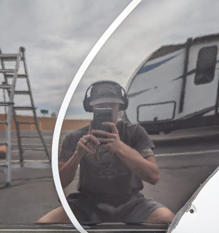 a professional detailer taking a picture of himself in the reflective paint to show the after results