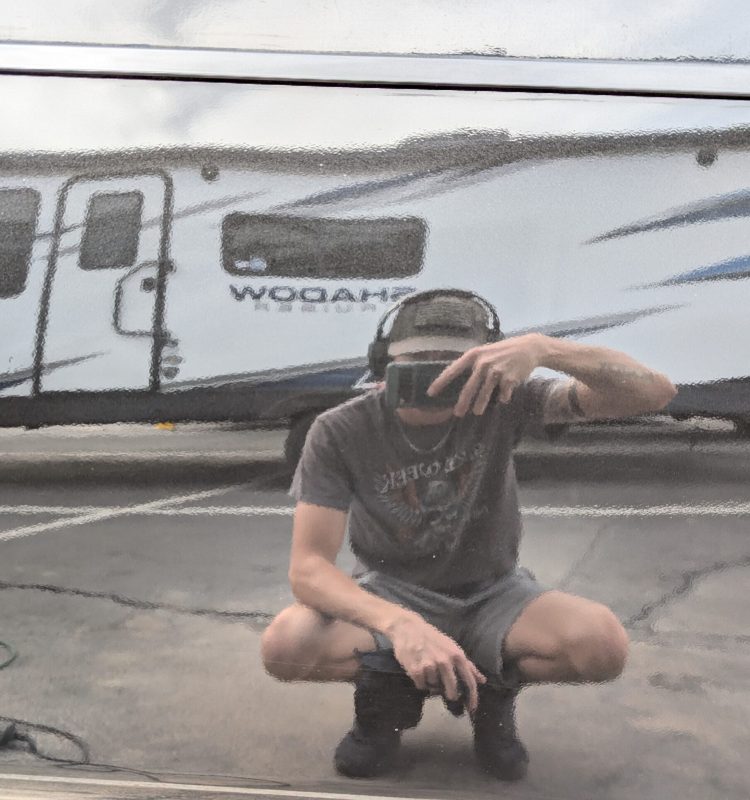 a professional detailer taking a picture of himself in the reflective paint he just corrected